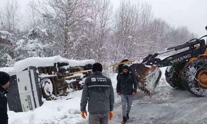 Karlı yolda yan yatan minibüsü iş makinesi ile kurtardılar